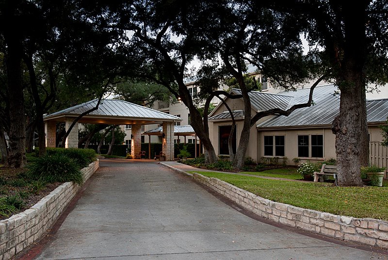 A beautiful house with a long driveway surrounded by lush trees.