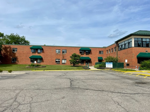 A brick building with green awnings surrounded by a well-maintained lawn and a clear sky.