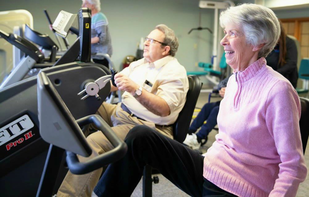 Elderly people enjoy exercising in a gym.