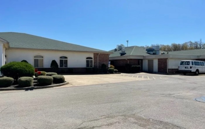 A view of a building with an adjacent parking lot on a sunny day.
