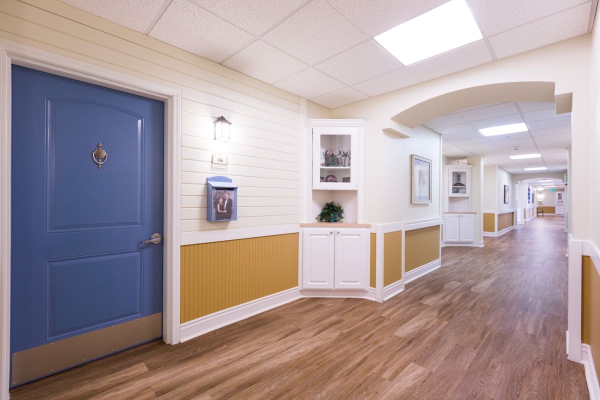 A well-lit hallway with wooden flooring and a blue door.