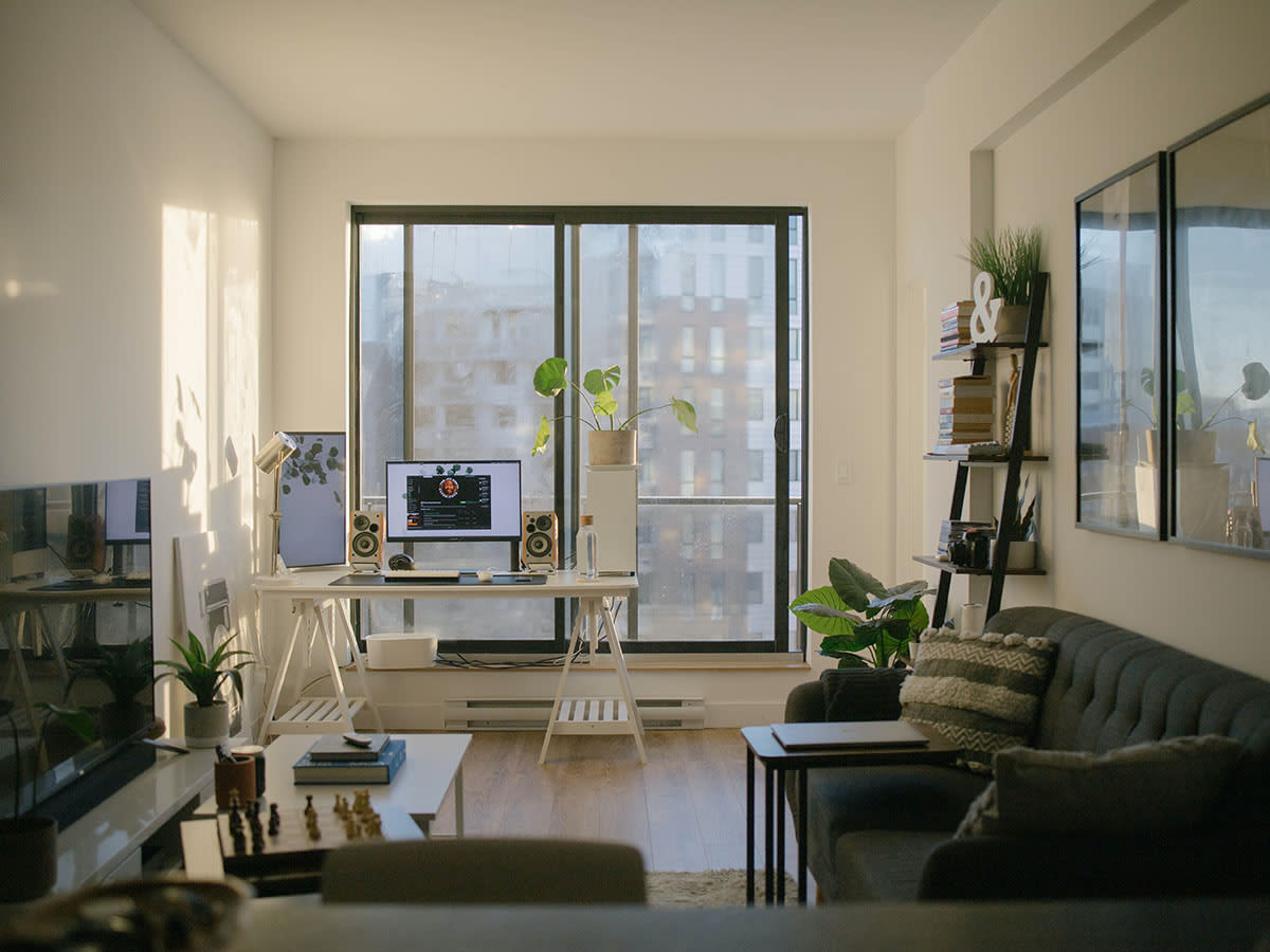 A bright and modern apartment living room with a home office setup.