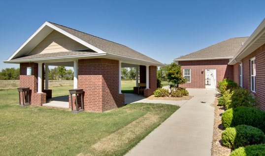 A suburban brick house with a well-maintained yard and driveway on a sunny day.