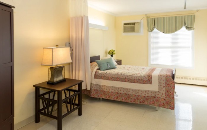 A cozy bedroom interior with a neatly made bed, bedside table, and lamp.