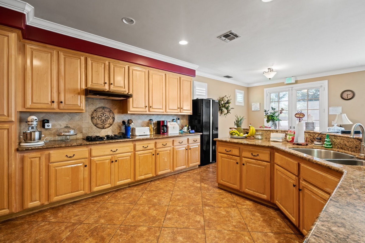 A spacious modern kitchen with wooden cabinets and tile flooring.