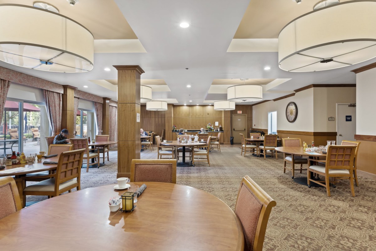A spacious dining room with neatly arranged tables and chairs, featuring warm lighting and elegant decor.