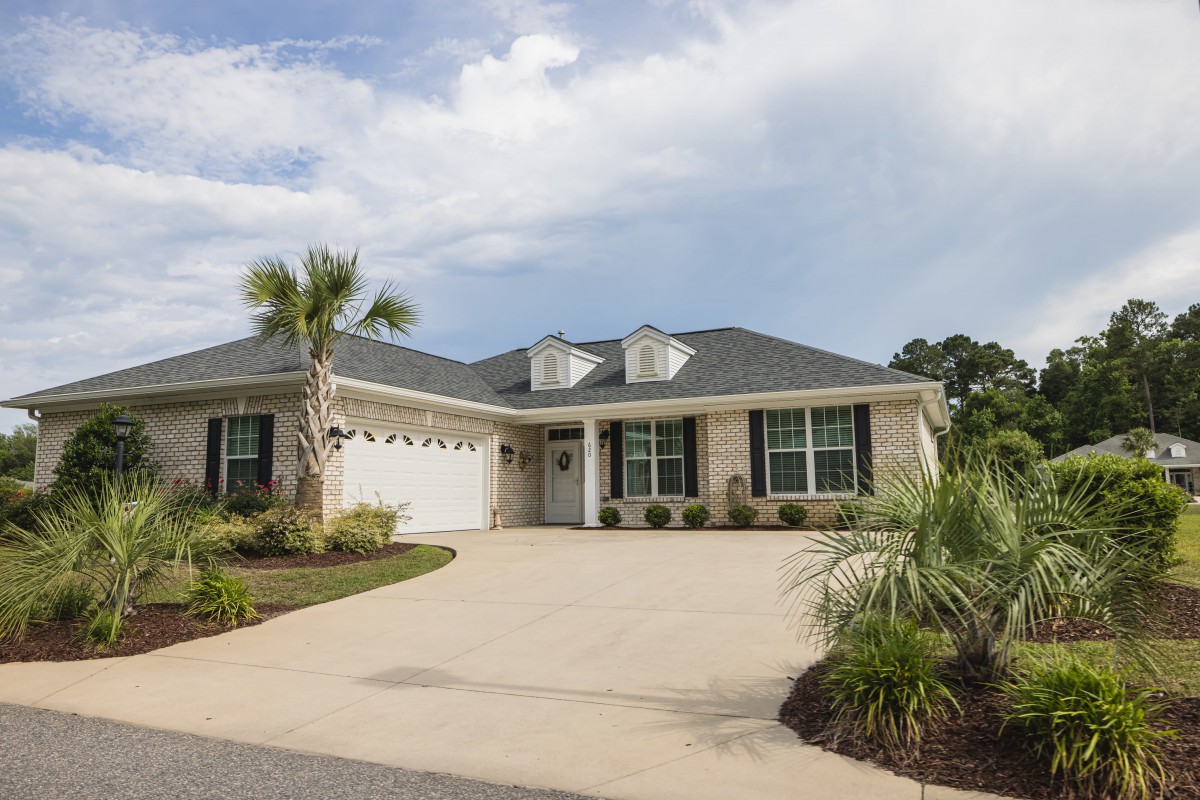 A single-story house with a two-car garage and palm trees in the driveway.