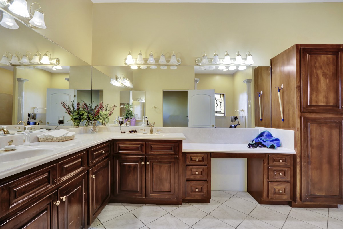 Spacious bathroom with a large mirror, wooden cabinets, and a bathtub.