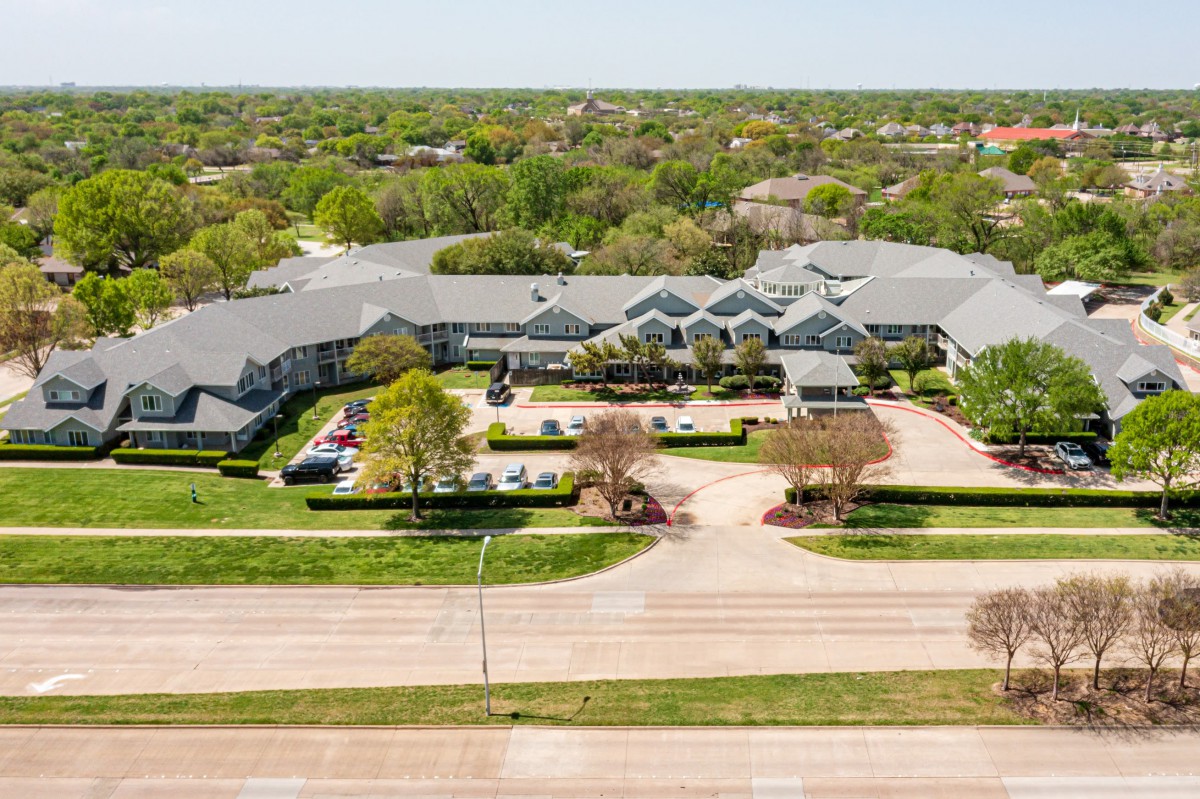 Aerial view of a residential building surrounded by trees and roads.