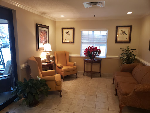 A cozy waiting area featuring comfortable seating, artwork, and decorative plants.