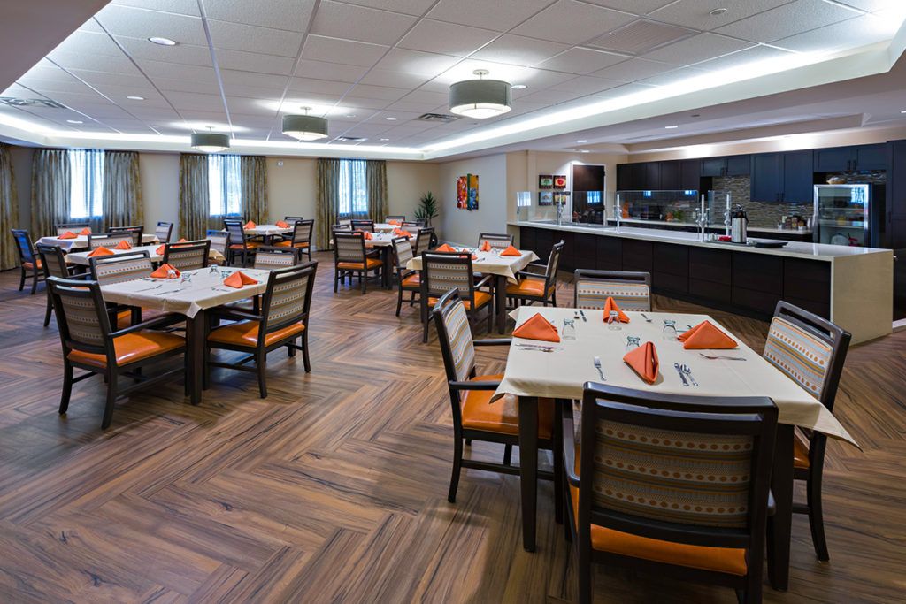 A well-arranged dining area with neatly set tables featuring orange napkins and modern decor.