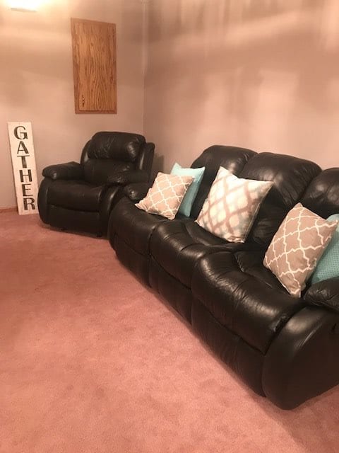 A cozy living room setup featuring a leather sofa and armchair with stylish pillows.