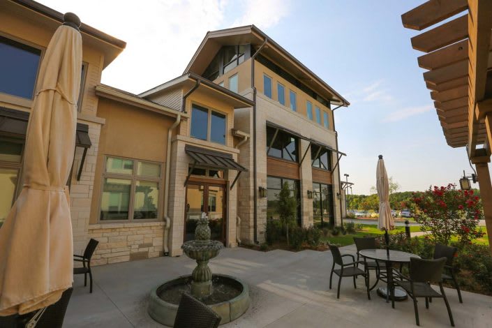 A modern building with outdoor seating and a central fountain on the patio.