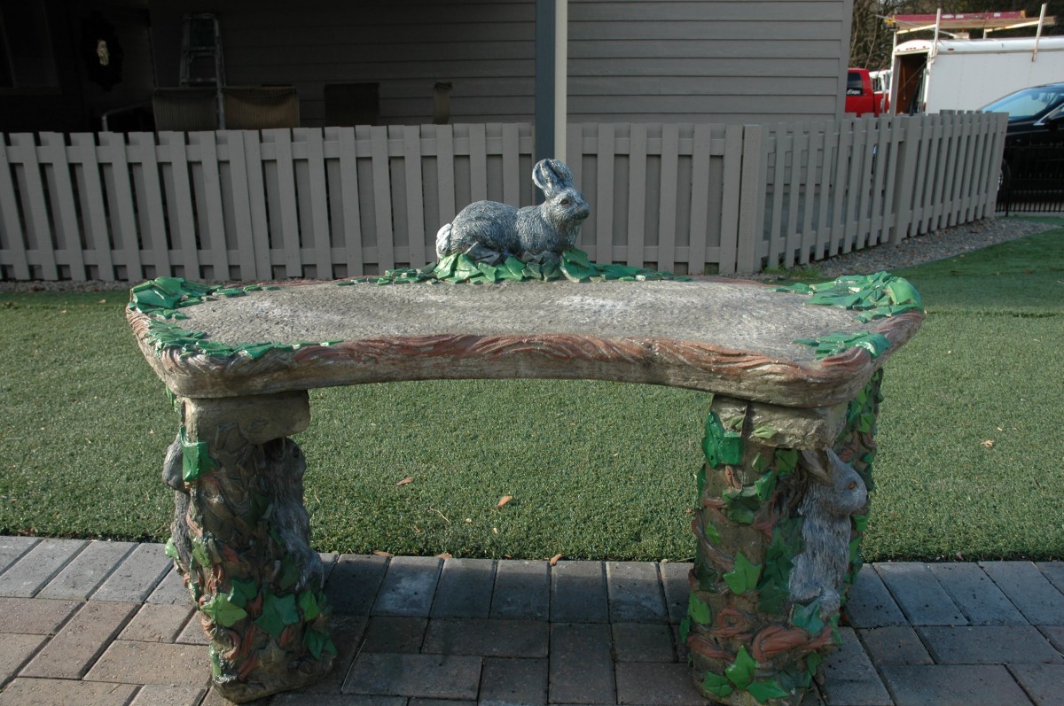 A decorative garden bench with a rabbit sculpture on top, set in an outdoor area.