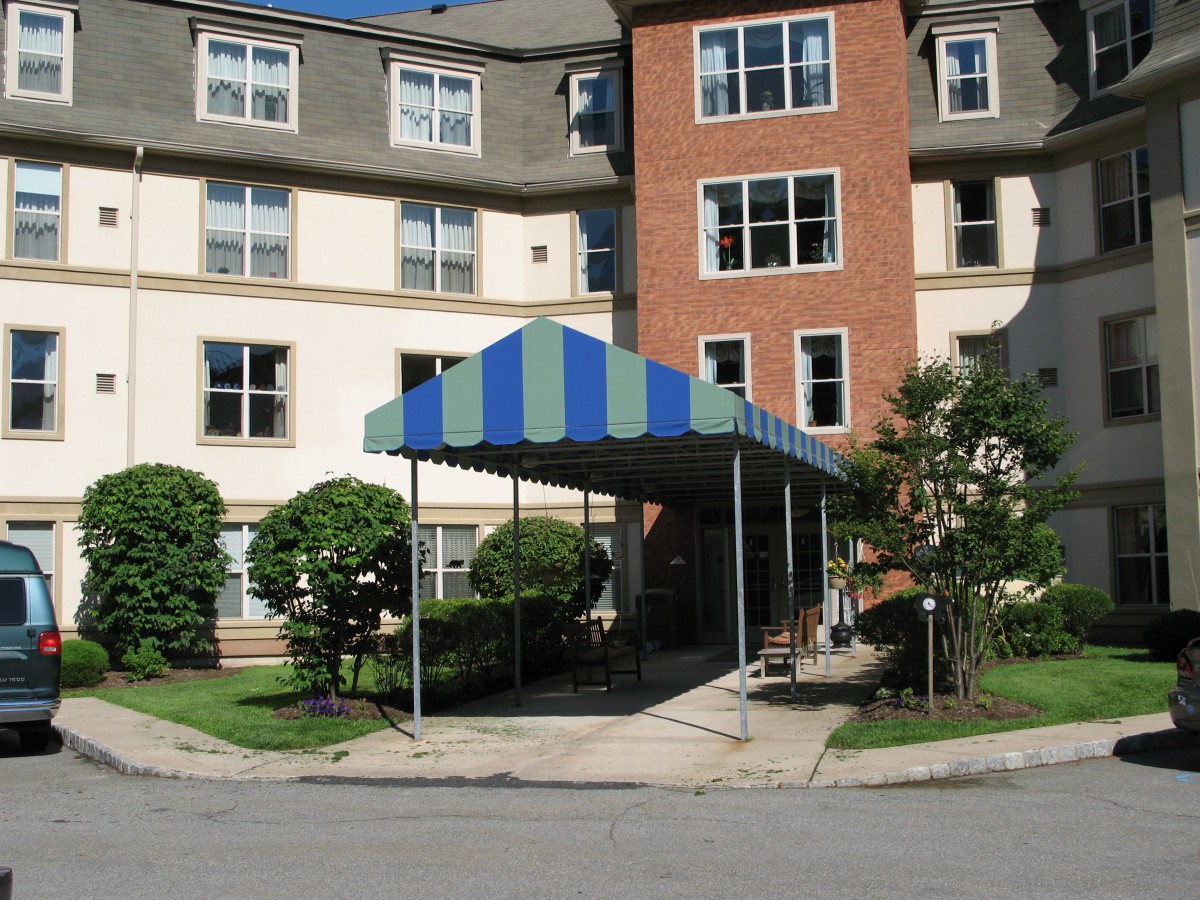 A residential building entrance with a blue and green striped awning.