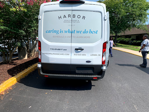 A rear view of a delivery van belonging to a company named Harbor, with the tagline 'caring is what we do best' displayed.