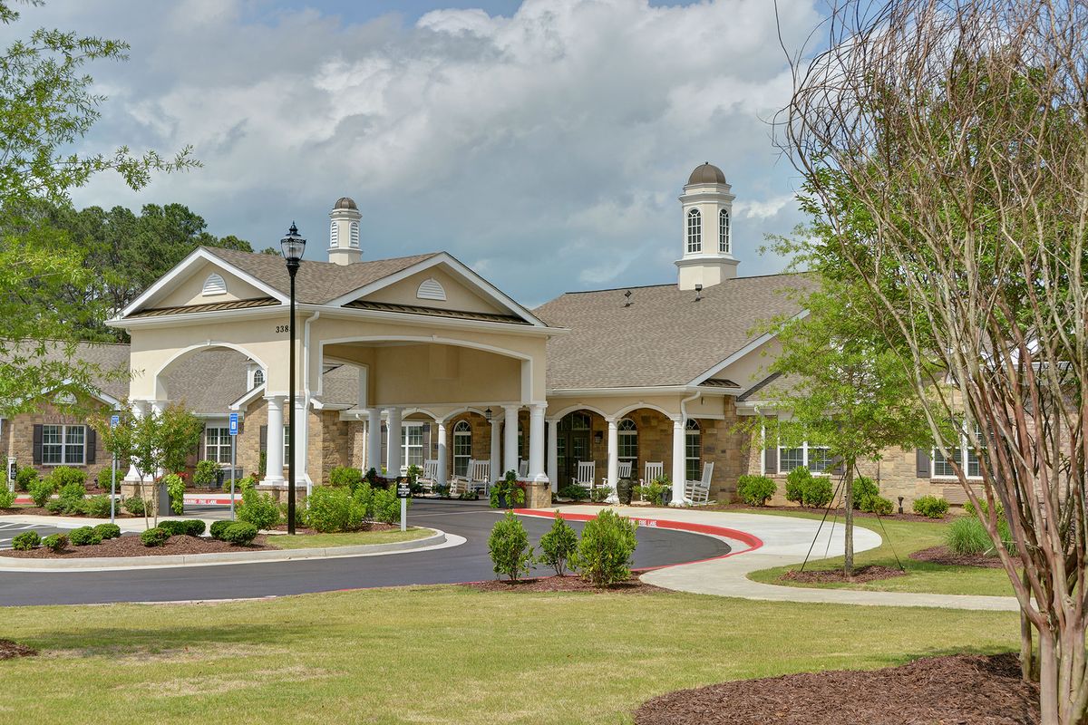 A well-maintained building with a landscaped garden and driveway under a cloudy sky.