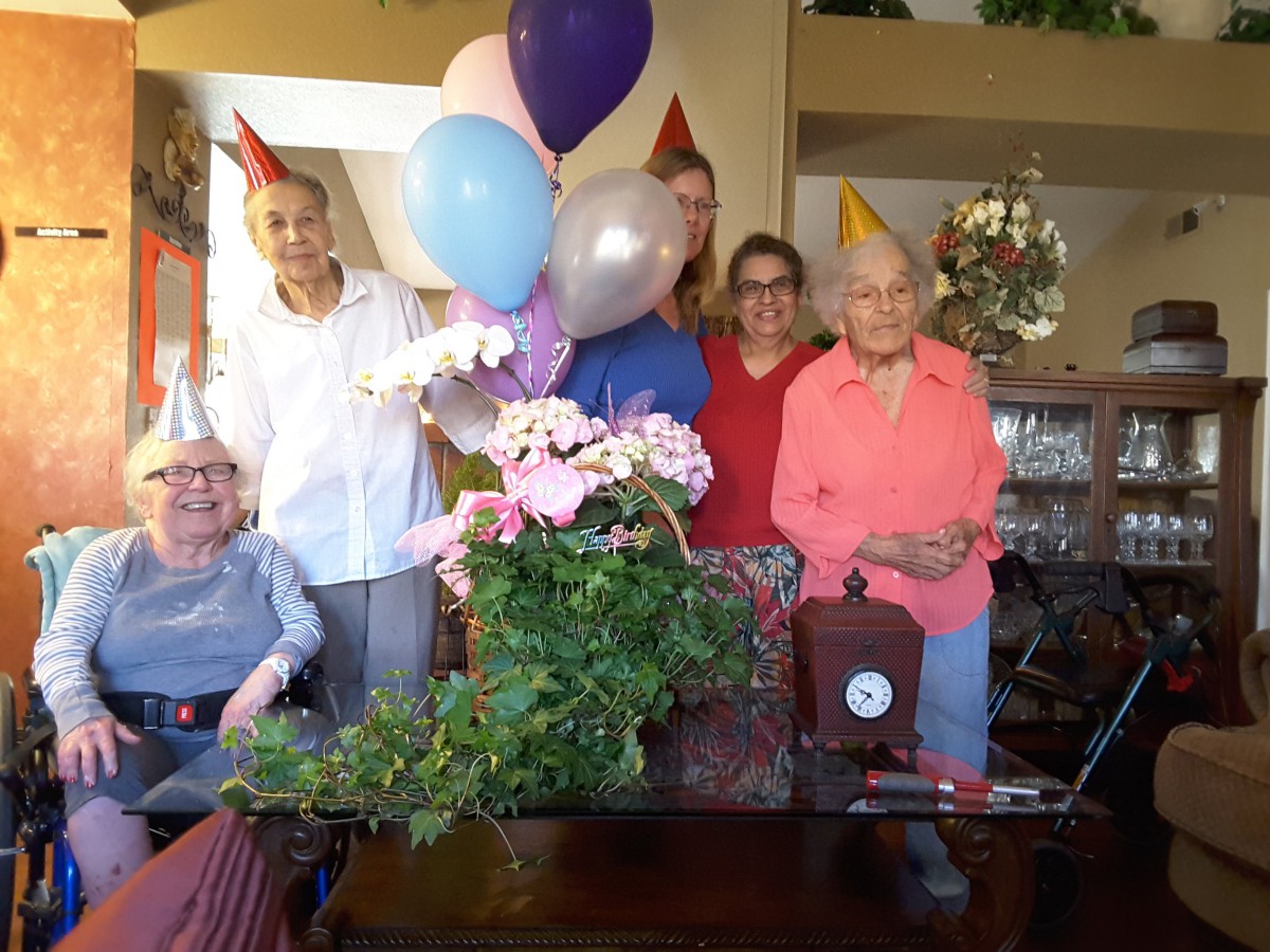 A group of people celebrating indoors with party hats and balloons.
