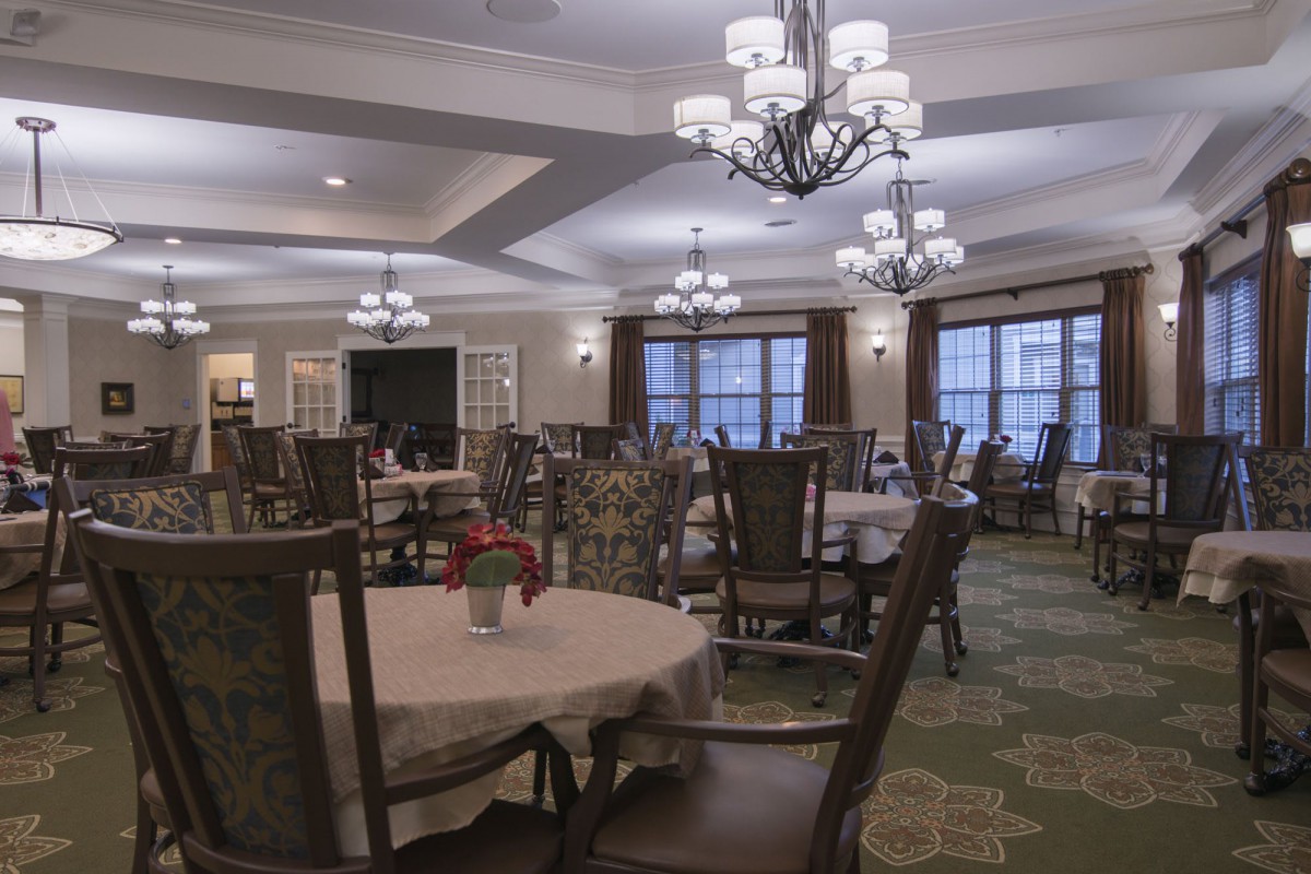 An elegant dining room with chandeliers and neatly arranged tables and chairs.