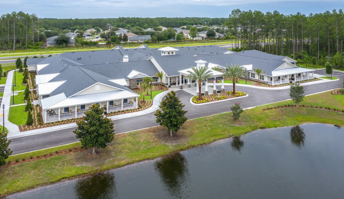 Aerial view of a large building complex surrounded by trees and situated near a lake.