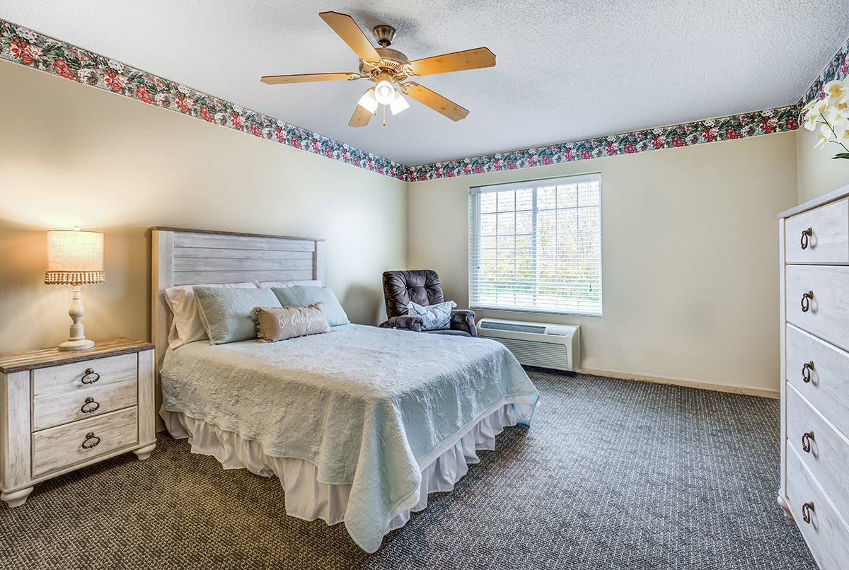 A cozy bedroom featuring a double bed, ceiling fan, and large window.