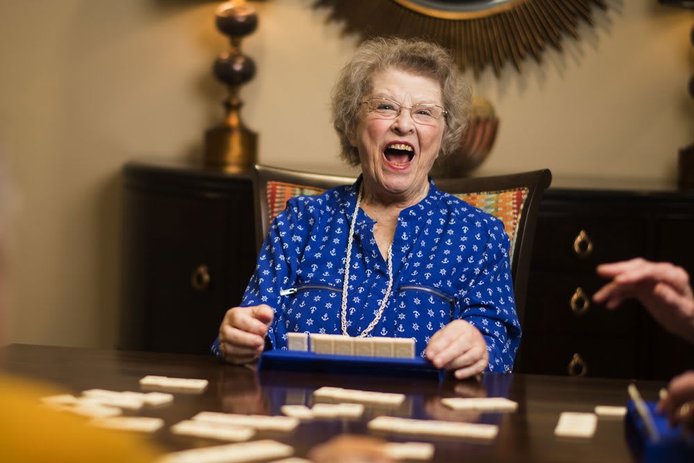 An elderly woman happily playing a board game indoors.