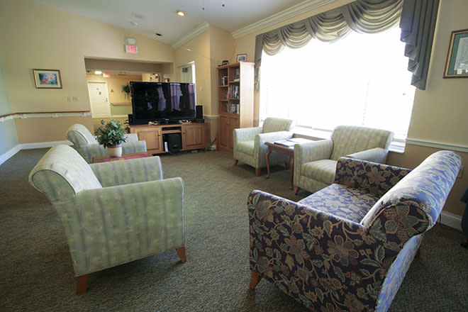 A cozy living room with comfortable seating and a large television, illuminated by natural light.