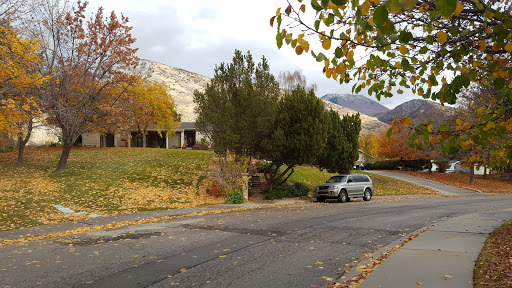 A serene autumn scene featuring a house surrounded by colorful trees and mountains in the background.