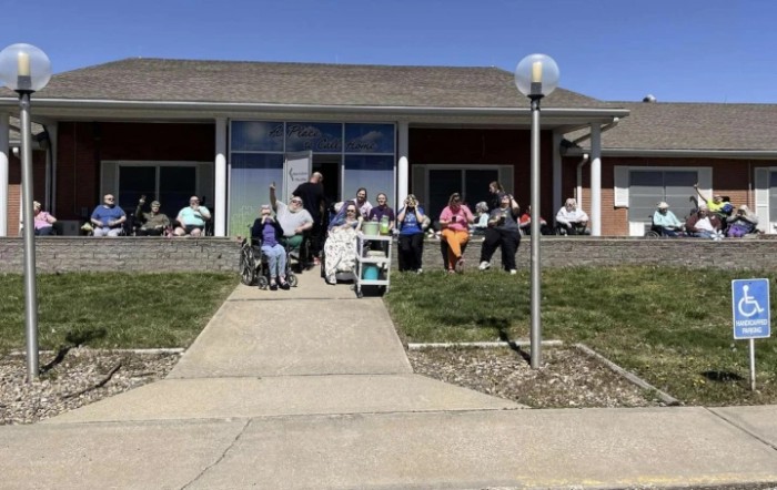 A group of people gathered outside a building on a sunny day.
