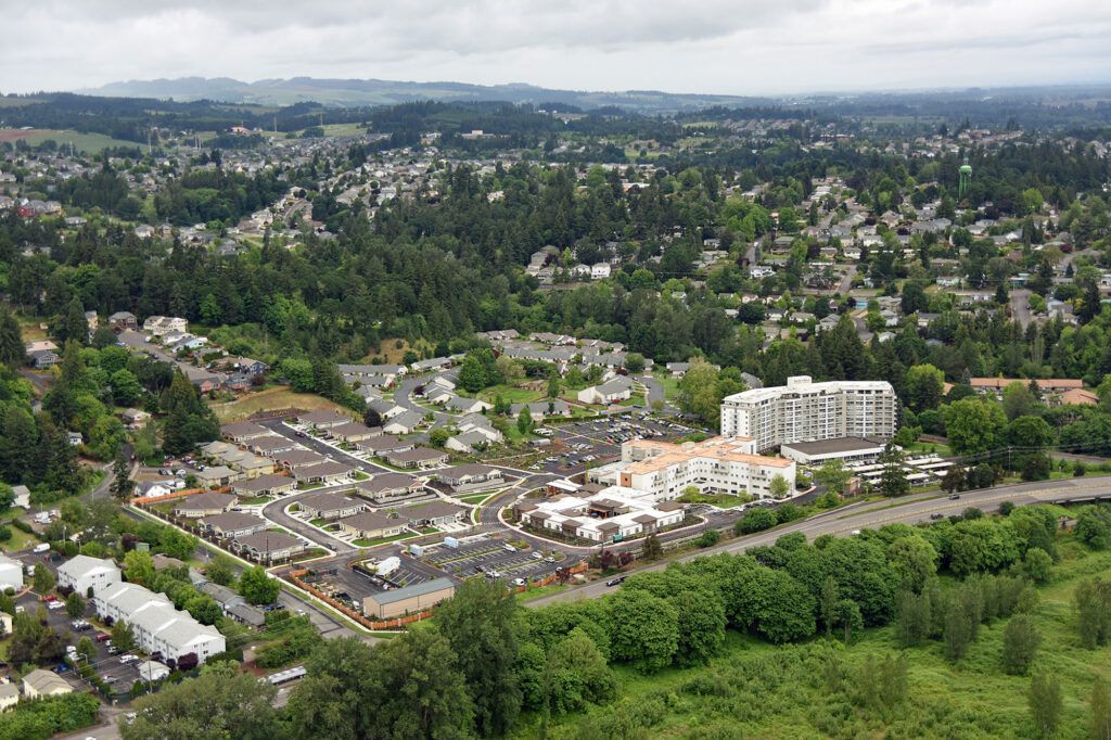 An aerial view of a suburban area with residential buildings and lush greenery under a cloudy sky.