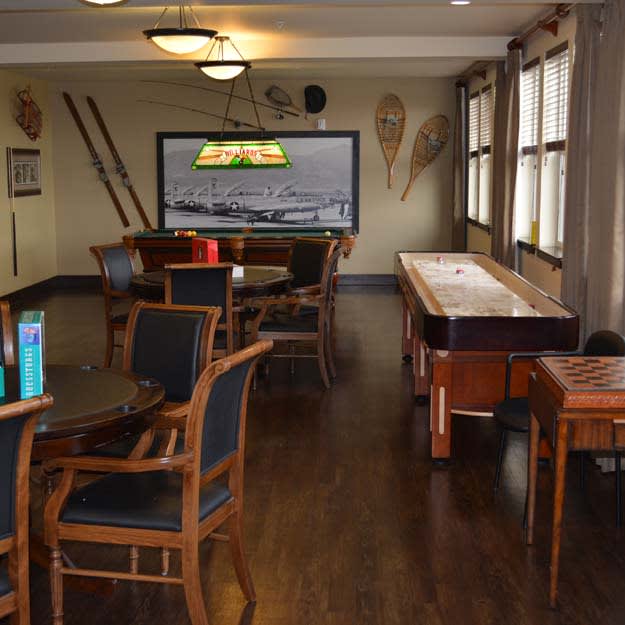 A cozy game room with a shuffleboard table, seating area, and television.