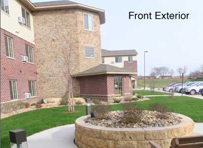 Front exterior view of a brick apartment complex with landscaped surroundings.