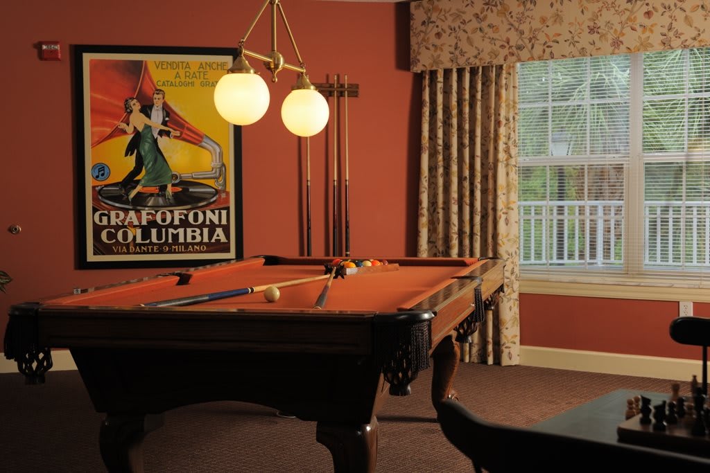 A cozy game room featuring a classic pool table, vintage poster, and elegant lighting.