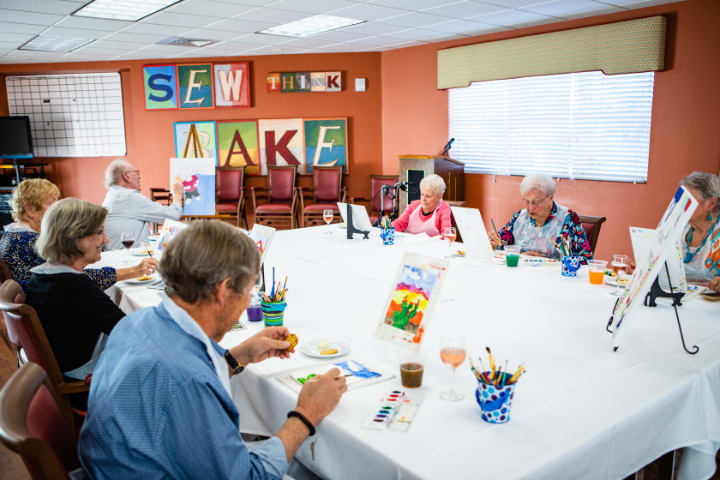 A group of seniors participating in an art class, engaging in creative activities around a table.