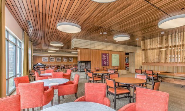 A modern cafeteria with red chairs and wooden ceiling.