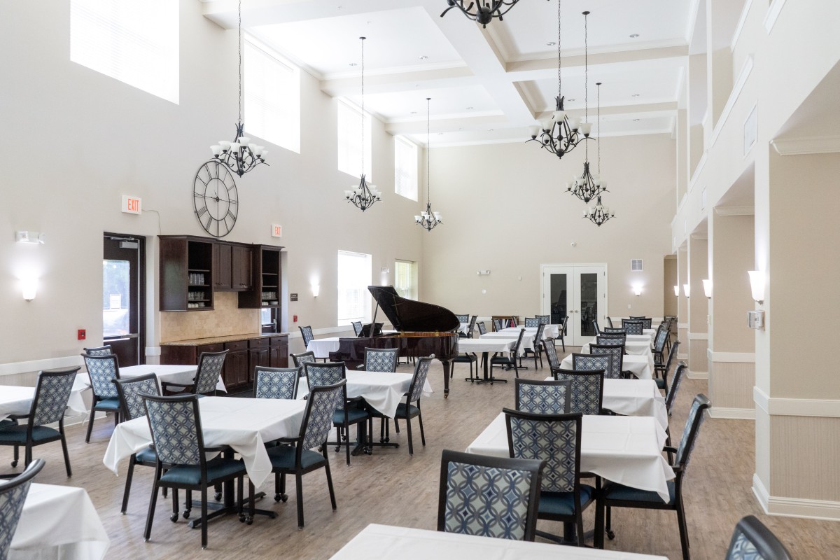 A modern dining room with elegantly set tables and a grand piano.