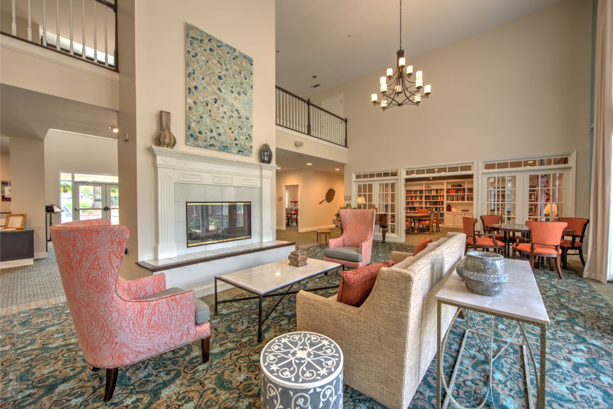 A spacious and elegantly designed living room featuring a modern fireplace, comfortable seating, and a sophisticated chandelier.