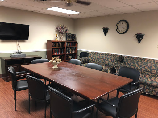 A well-furnished meeting room equipped with a large conference table, chairs, and multimedia facilities.