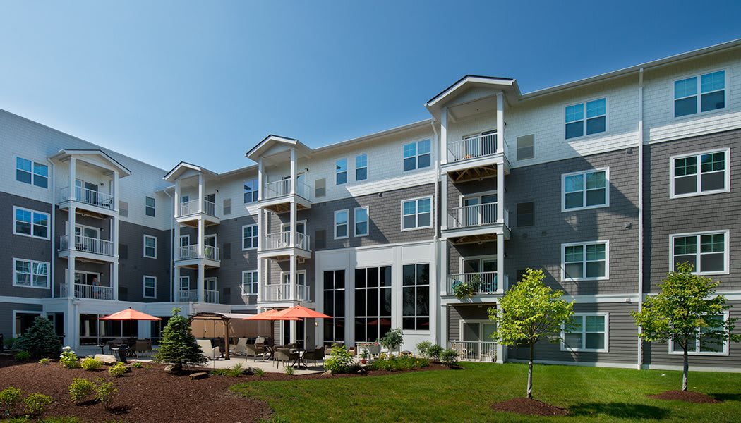 Modern apartment building with balconies and outdoor seating area.