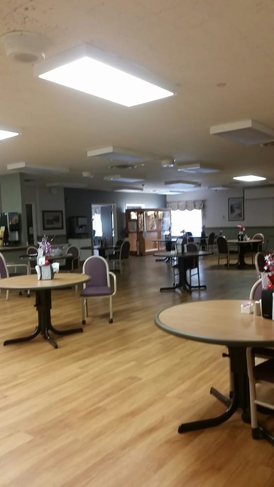 An empty dining area with tables and chairs arranged on a wooden floor.