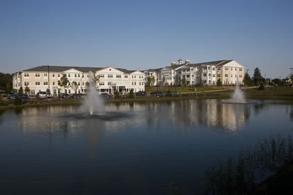 A tranquil view of apartment buildings with fountains reflecting in a lake.