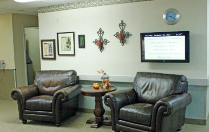 A cozy waiting room with leather chairs, decorative wall art, and a TV.