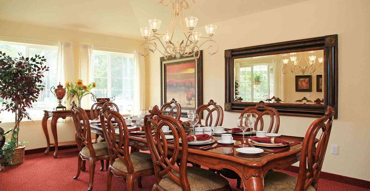 An elegant dining room with a beautifully set table, ornate chairs, and a chandelier.