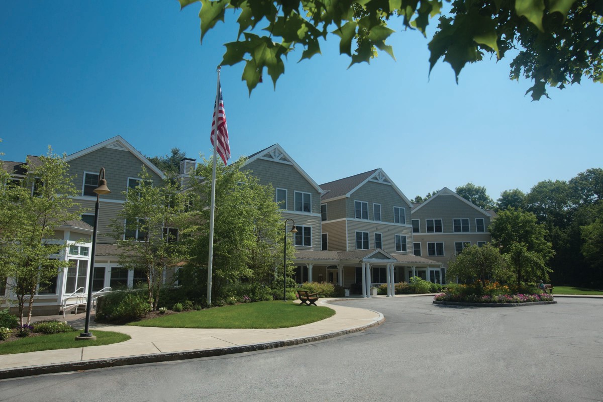 A residential building with an American flag and surrounding greenery on a sunny day.