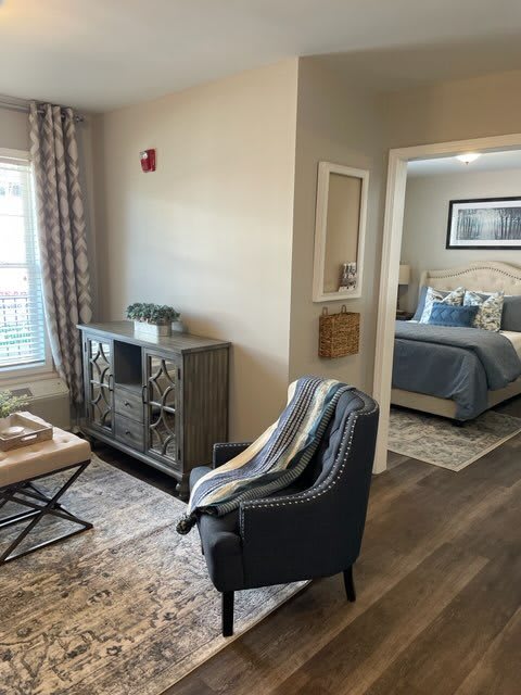 A stylishly designed living area with a view into the bedroom, featuring modern decor and comfortable furnishings.
