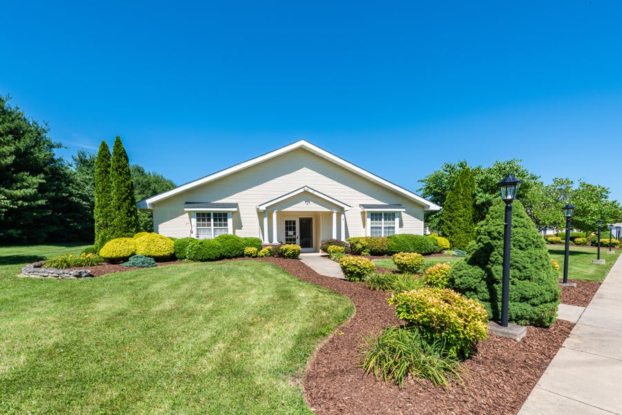 A well-maintained residential property with a lush green lawn and landscaped garden under a clear blue sky.