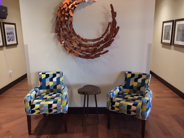 A modern interior setup featuring two colorful chairs and a small table, complemented by a circular wall artwork.