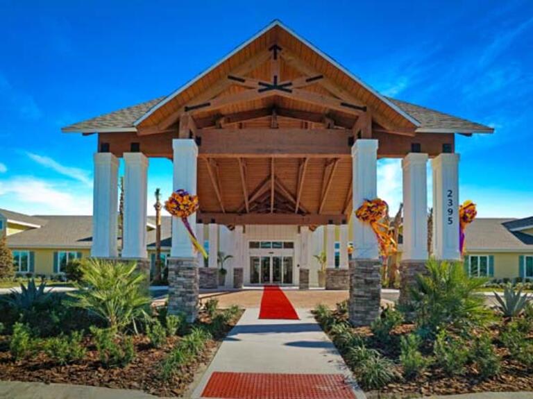 A grand entrance with a red carpet leading to a tropical-themed building under a clear blue sky.