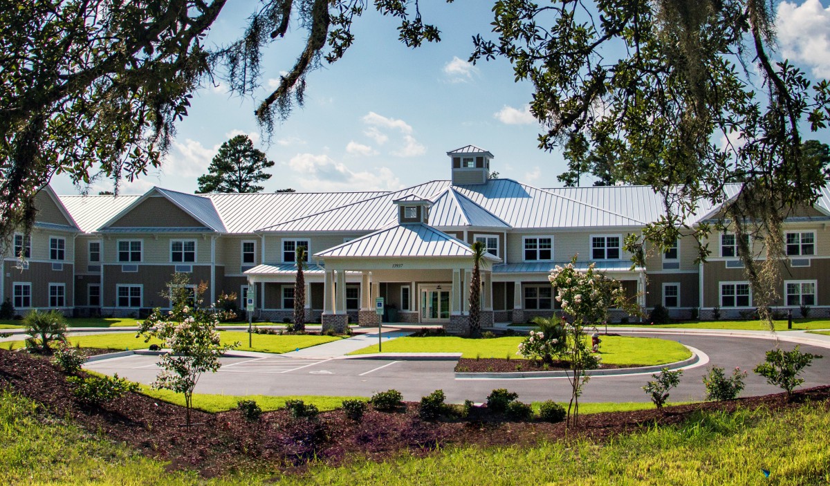 A large, elegant building surrounded by greenery under a clear blue sky.