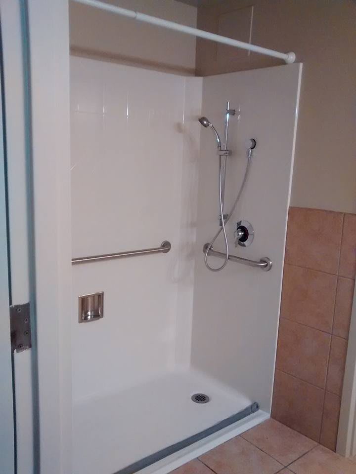 An accessible shower stall with a grab bar and adjustable showerhead.
